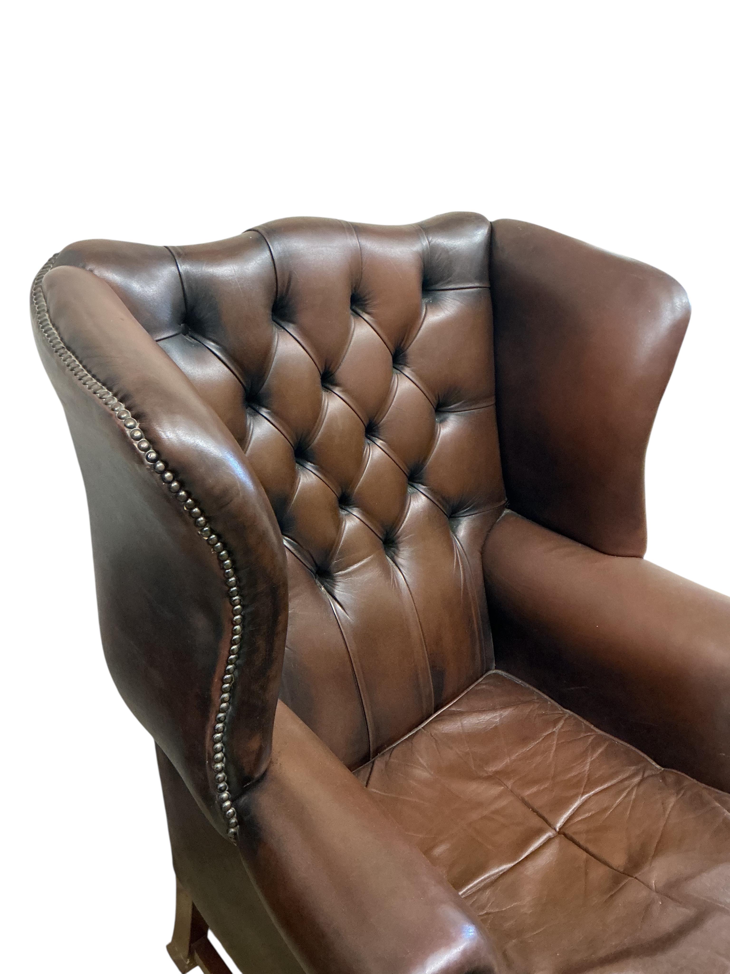 A reproduction George III style buttoned brown leather wing armchair, width 84cm, depth 70cm, height 110cm